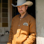 Eric Nelsen wearing "The Stockshow" Canvas Bomber jacket standing in a doorway wearing a cowboy hat. 