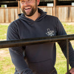 Ryan Dukes leaning on a fence with Stockyard Supply Co Charcoal hoodie. 