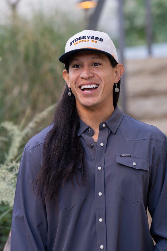 JP Guana wearing a Stockyard Supply Co hat with a faded navy blue performance pearl snap Stockyard Supply Co Shirt on.