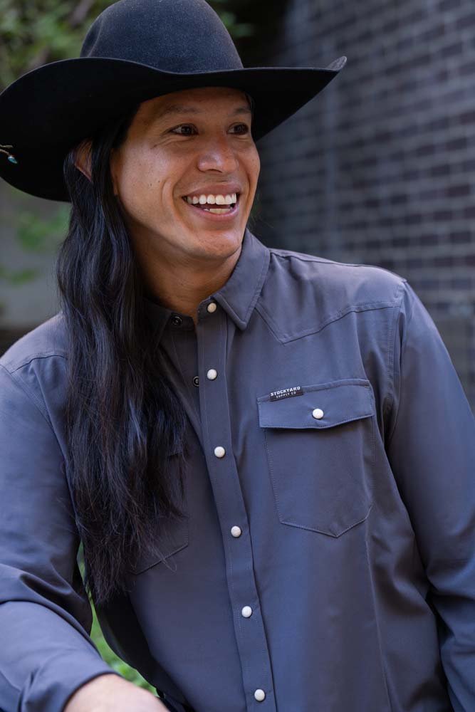 JP Guana wearing a black cowboy hat with a faded navy blue performance pearl snap Stockyard Supply Co Shirt on.