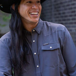 JP Guana wearing a black cowboy hat with a faded navy blue performance pearl snap Stockyard Supply Co Shirt on.