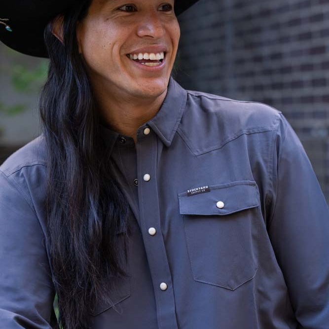 JP Guana wearing a black cowboy hat with a faded navy blue performance pearl snap Stockyard Supply Co Shirt on.