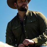 Ryan Dukes wearing a faded olive pearl snap button down shirt sitting on a horse