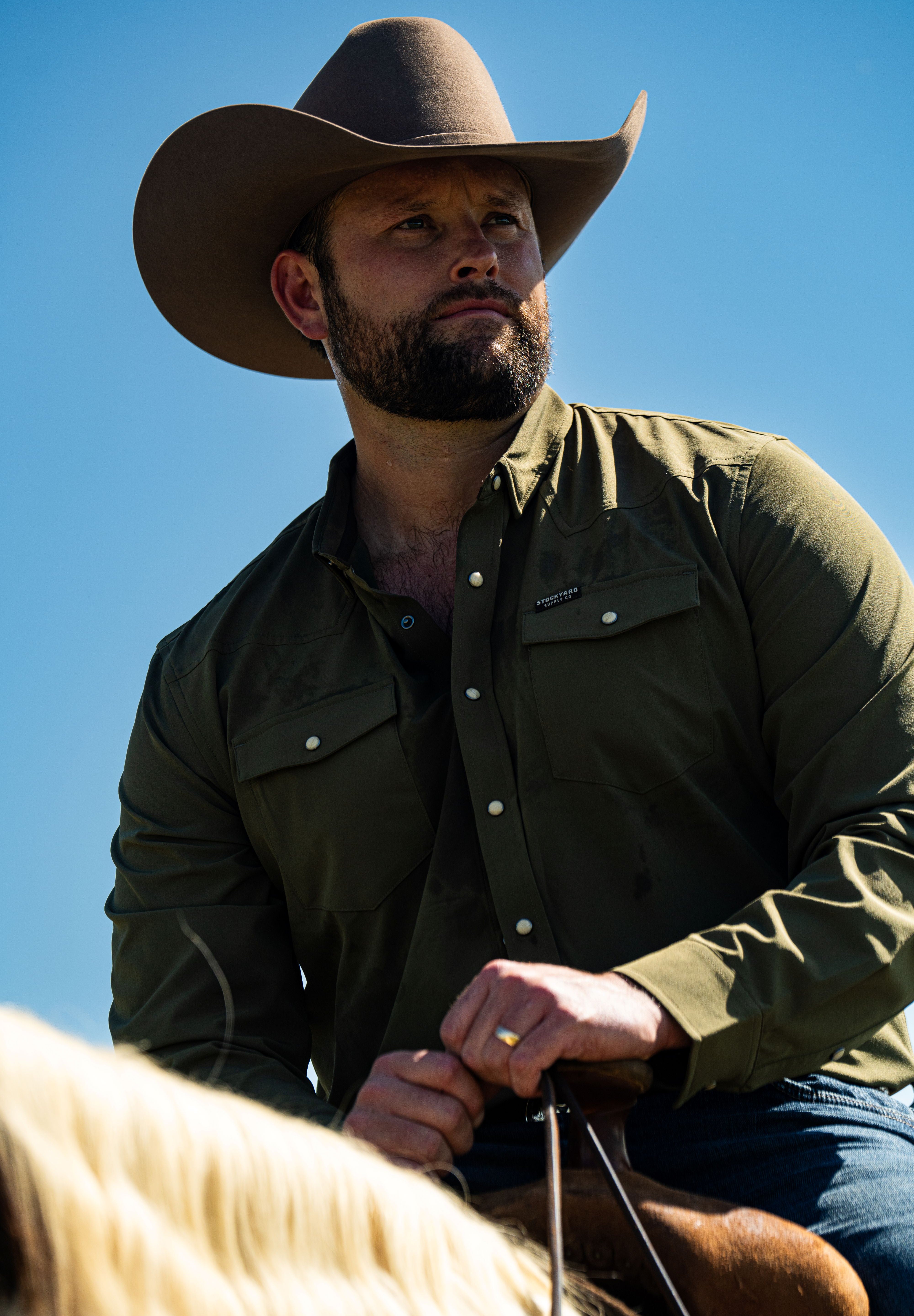 Ryan Dukes wearing a faded olive pearl snap button down shirt sitting on a horse