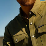 Eric Nelsen wearing a faded olive pearl snap button down shirt close up shot of shirt