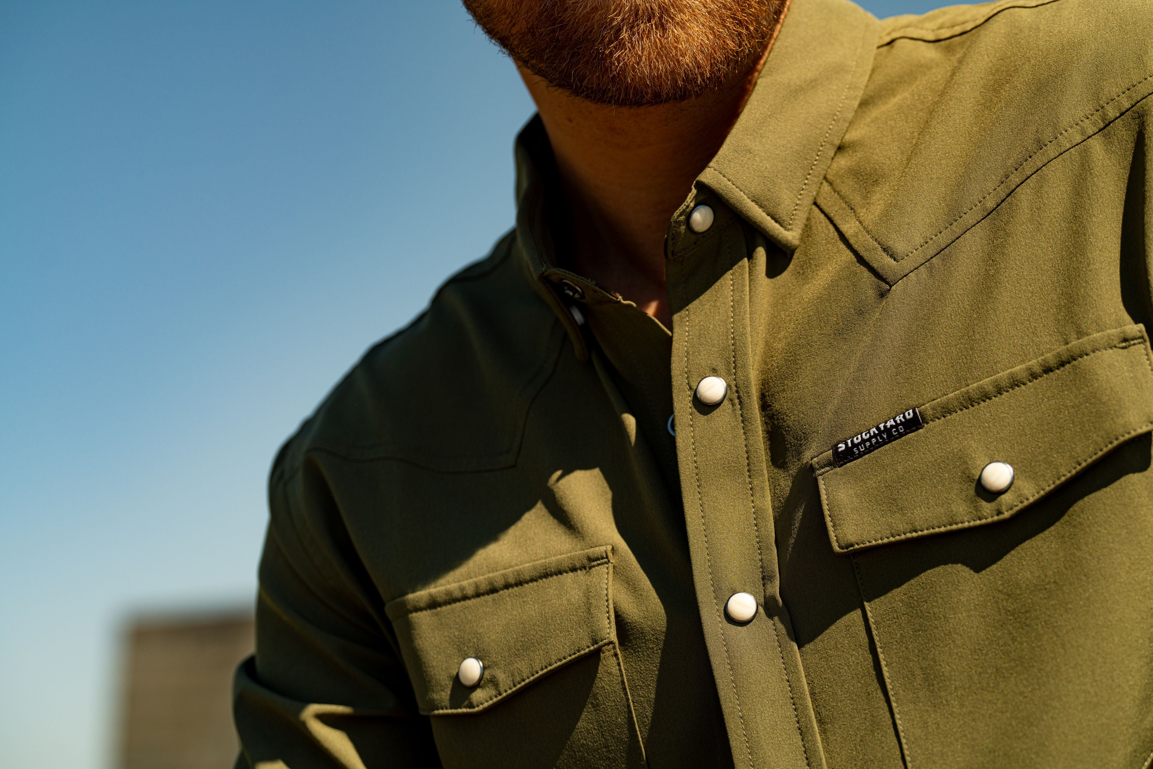 Eric Nelsen wearing a faded olive pearl snap button down shirt close up shot of shirt