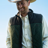 Eric Nelsen waring a tan cowboy hat, cream performance pearl snap shirt with the Rodeo King Olive and chocolate vest unzipped.  