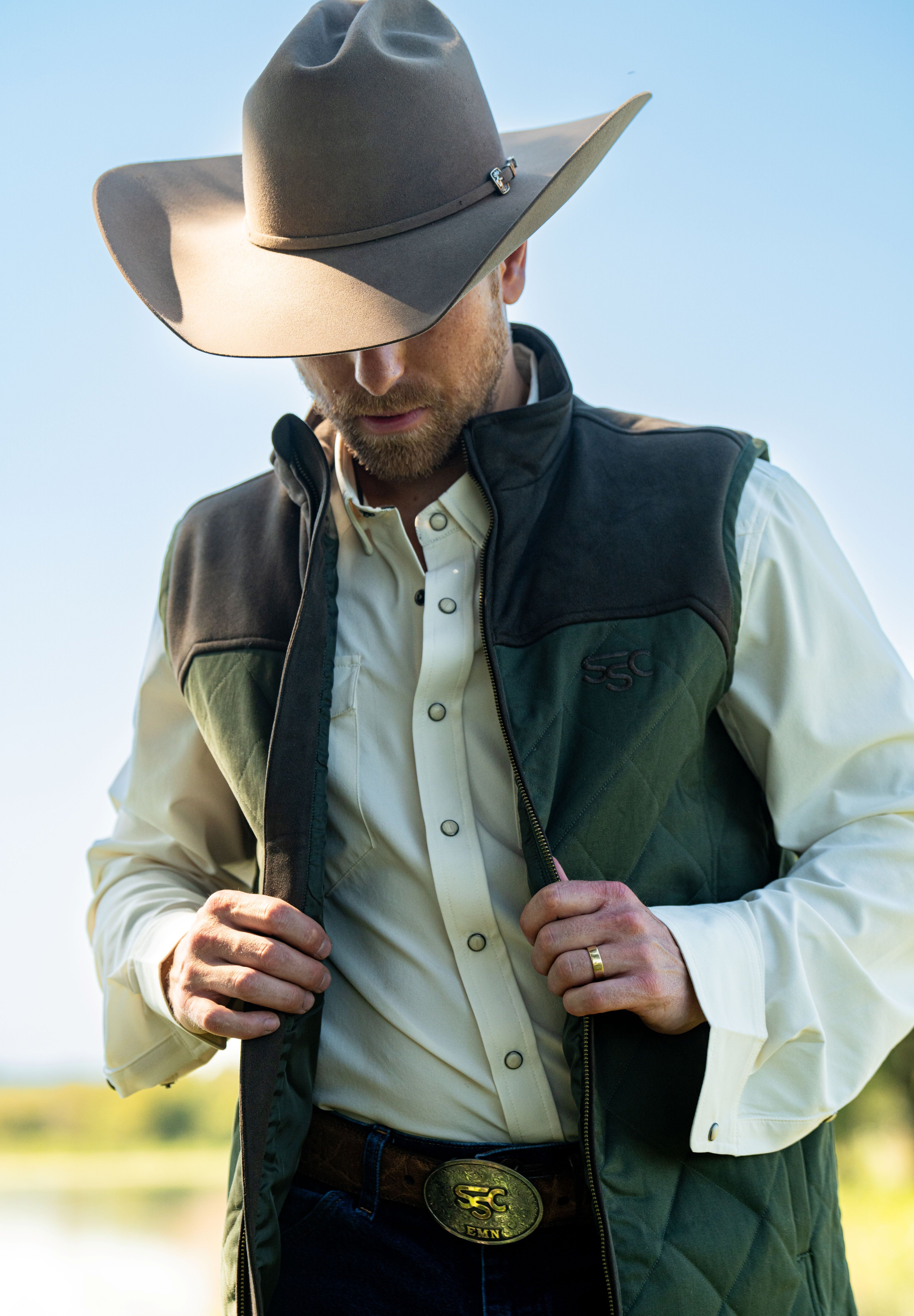 Eric Nelsen wearing Chocolate and Olive vest with cream pearl snap performance underneath with cowboy hat. 