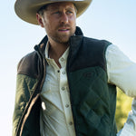 Eric Nelsen waring a tan cowboy hat, cream performance pearl snap shirt with the Rodeo King Olive and chocolate vest unzipped.  