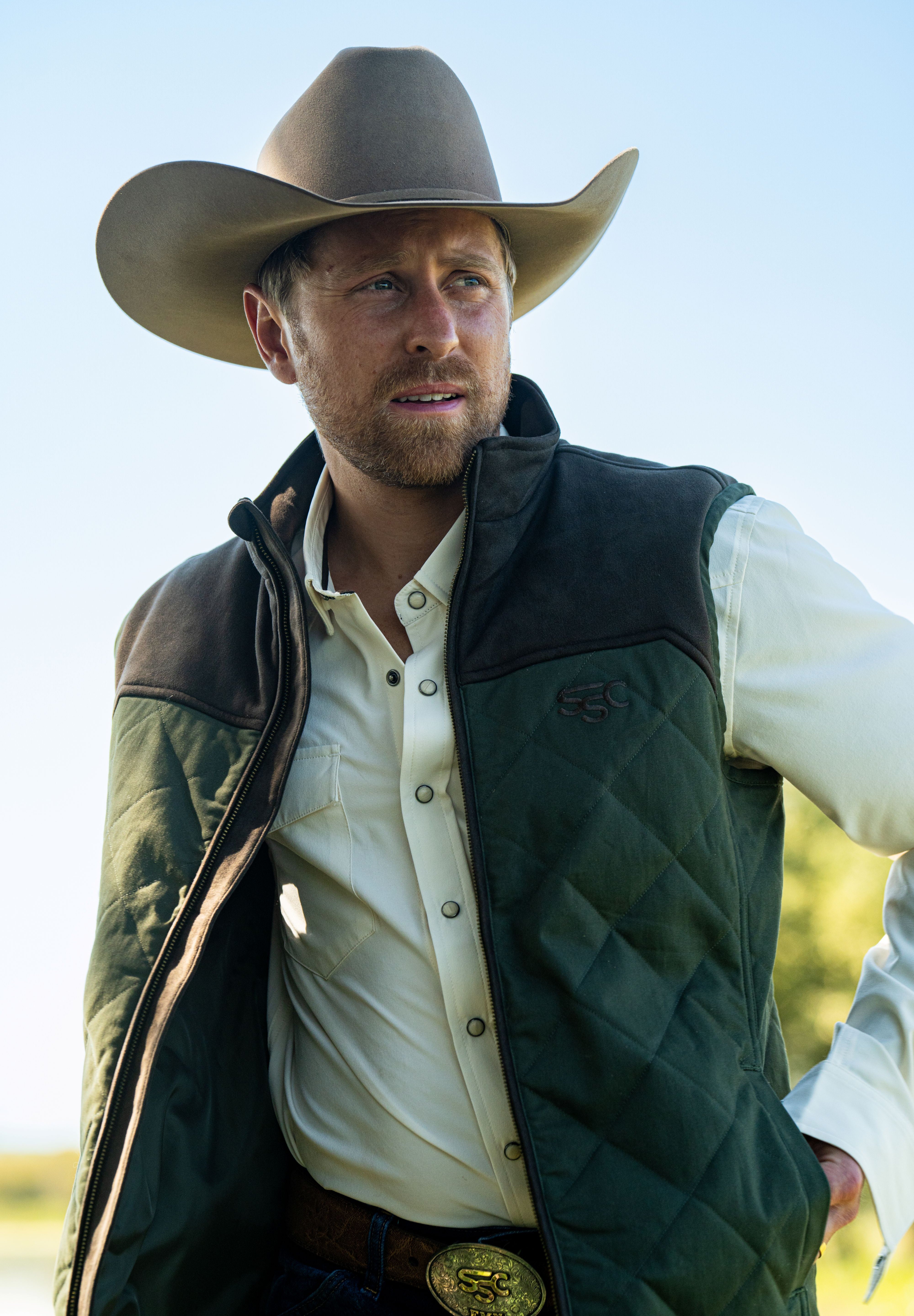 Eric Nelsen waring a tan cowboy hat, cream performance pearl snap shirt with the Rodeo King Olive and chocolate vest unzipped.  