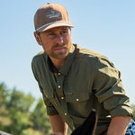 Eric Nelsen wearing the Coyote colored Champion hat and faded olive long sleeve performance pearl snap mounting a horse.