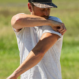 Eric Nelsen wearing a white shirt with the Commander Stockyard Supply Co hat with a black mesh and camo pattern brim rolling up his sleeves.