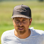 Eric Nelsen wearing a white shirt with the Commander Stockyard Supply Co hat with a black mesh and camo pattern brim.